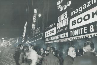 Crowd of men congregate in front of building with large sign reading, Times Square Open 24 hrs …