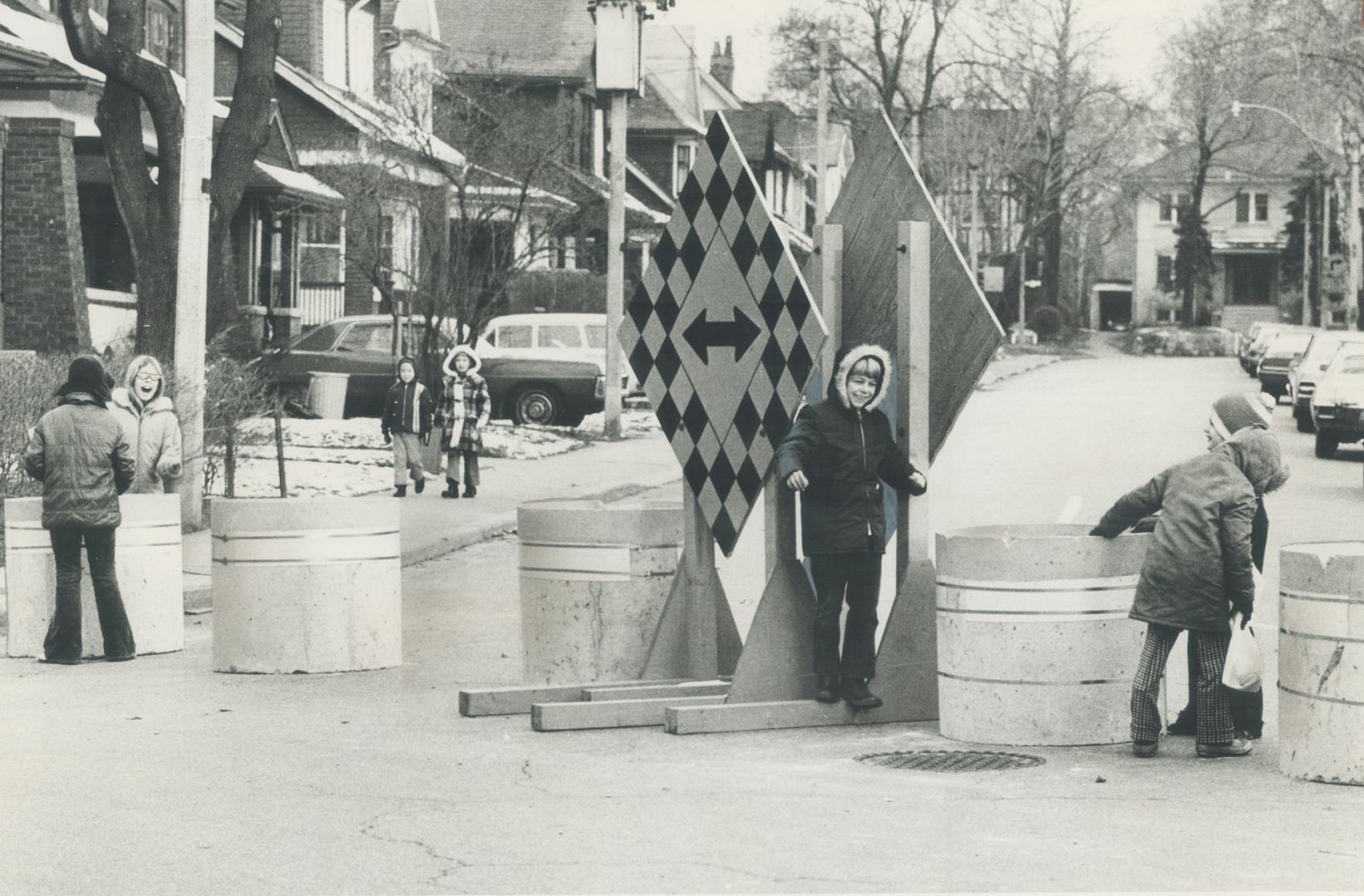 Children play among Moore park street barricades (above) as cars pass by (right)