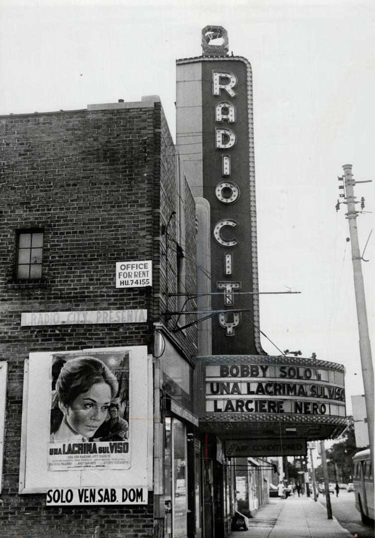 Marquee sign; vertical section reads Radio City; billboard section below reads, Bobby Solo Una …