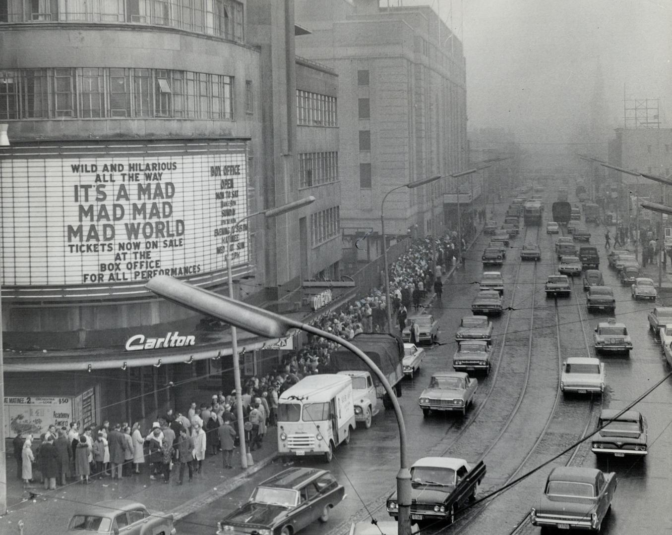 Overhead street view of people lined up around block outside cinema. Sign above entrance reads,…