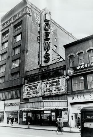 Two-storey building with vertical marquee sign on roof reading, Lowe's, stands between two larg…