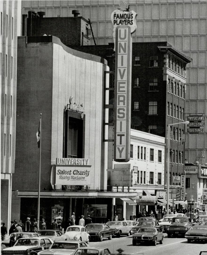 Streetscape with view of vertical marquee sign attached to flat-faced building, reading, Univer…