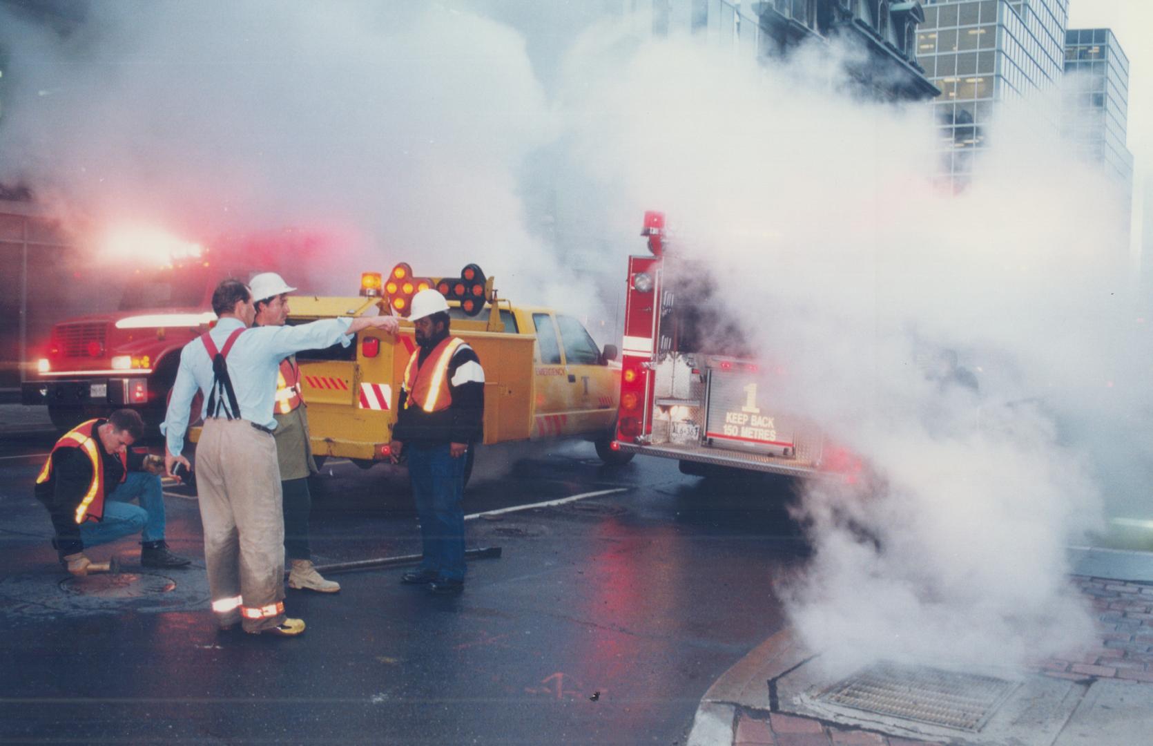 Image shows workers and emergency vehicles by the water main burst.