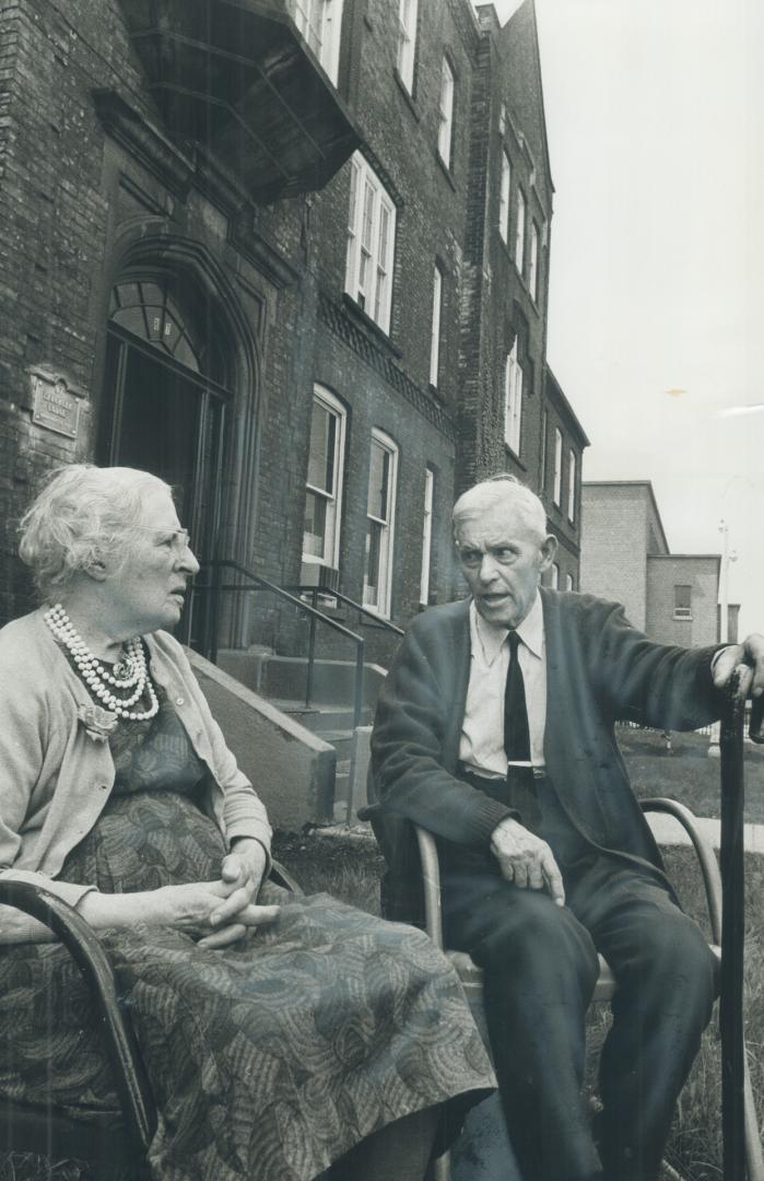 watching busy downtown life go by, Isabel Loudon, 89, and James Collier, 81, sit in front at Laughlen Lodge, a residence for senior citizens on Elm St(...)