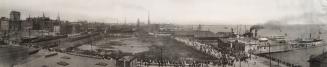 A black and white panoramic photo of the city in 1907. In the foreground are rooftops. A large …