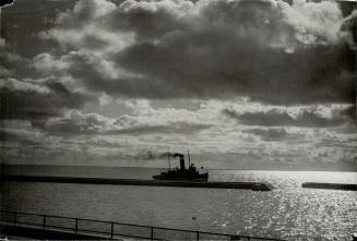 Image shows a boat on the lake under the dark clouds.