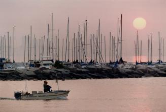 Image shows a person on the boat with a lot of boats in the background.