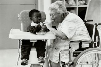 Young and old: Seven Oaks Home for the Aged resident Florence Comeau feeds 18-month-old Kofl in the day-care centre that's part of the Scarborough home