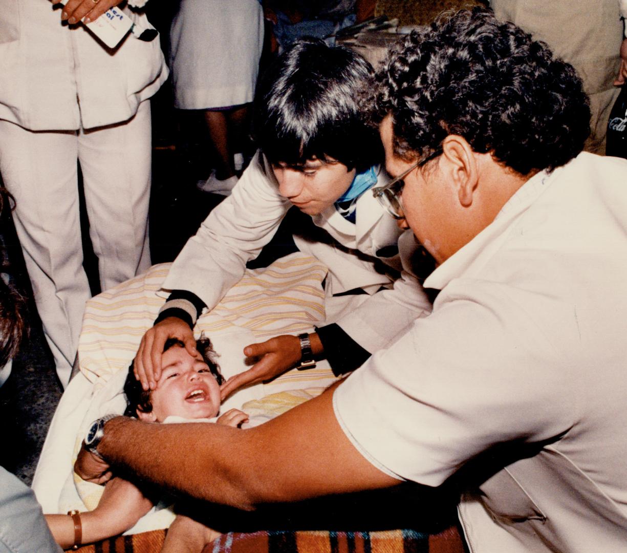 In safe hands: Doctors in Mexico City examine a child in an outdoor hospital Friday night, close to where some of the worst quake damage occured