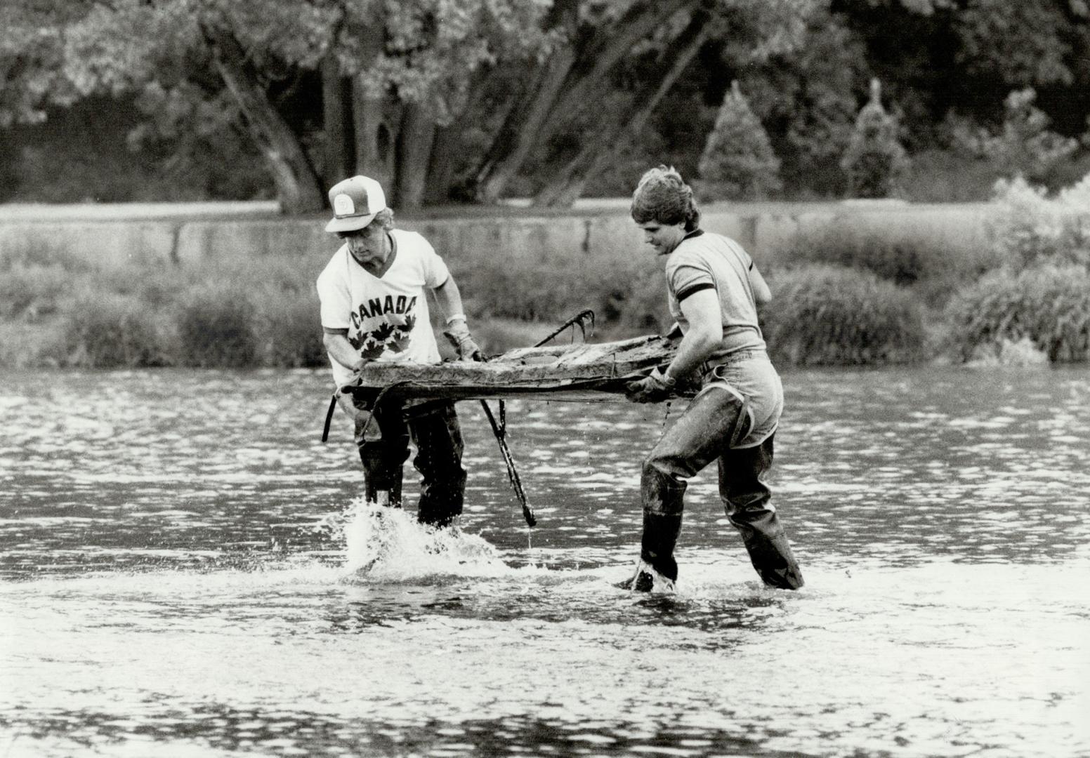 Jim Kroetsch, 22, left, and Gord Sarazin, 24, working for a program called SCOUR, carry rusted car door from the Humber River, near the Old Mill Resta(...)