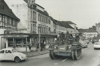 The wine-and-roses bliss of the village of Rudesheim on the banks of the Rhine is shaken by a fleet of tanks as the West German Army goes on manoeuvre(...)