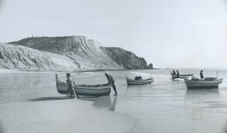 Algarve coast fishermen haul their boats ashore on a beach near Sagres