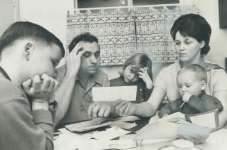 Factotry worker, John Noseworthy, examines a pile of unpaid bills with his wife, Ruth