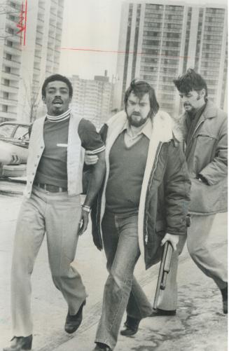 Police with holdup suspect, Metro police Constable Roy Teeft, carrying rifle, escorts Wayne Patton from apartment on Brahms Ave. today following his arrest on a charge of armed robbery