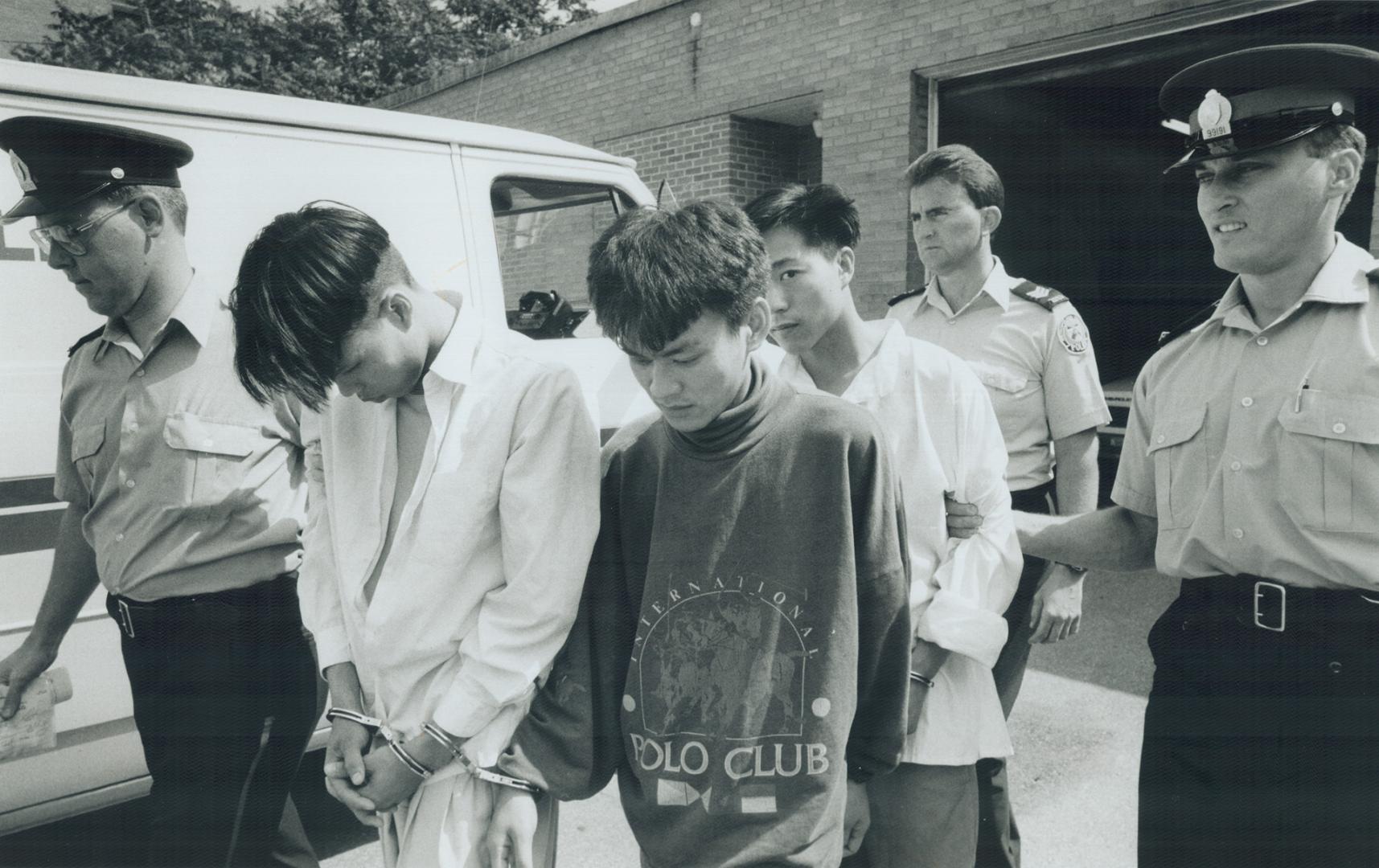 Armed Robbery suspects under arrest, Officers lead Hung Hoang, 20, left, Dung Lieu, 23, and Minh Ly, 24, from cells to a police van on their way to court after charging them with robbery