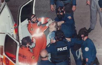 Ambulance workers put saline solution into a suspect's eyes after police lobbed tear gas into a Yonge St