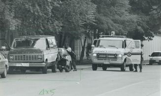 Double check: A police officer uses a mirror on a stick to check the interior of a van while another covers him after a suspect, below, who was sleeping in the van is bundled into a paddy wagon