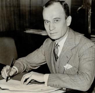 H. Ruper Bain in his Bay St., Toronto, office. His enterprises are extending throughout Canada and into the United States and England