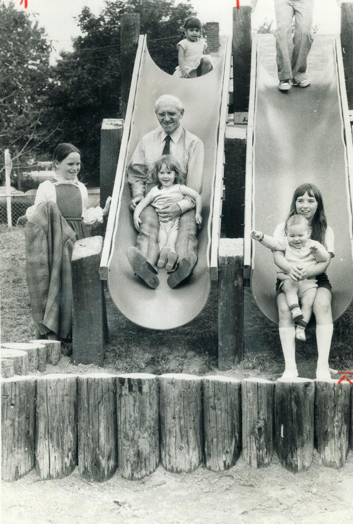 Attorney-general Dalton Bales takes a slide with 3-year-old Debbie Simkins in the adventure playground opened Saturday at Spring Garden Public School,(...)