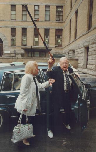 Comes out swinging: An angry Harold Ballard arrives at court yesterday for his son Bill's trial on a charge of assaulting Yolanda Ballard, left