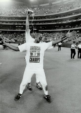 Singing in the Rain: Derek Bell doesn't seem to mind the dousing he's getting from Turner Ward as the Jays celebrated their American League East title