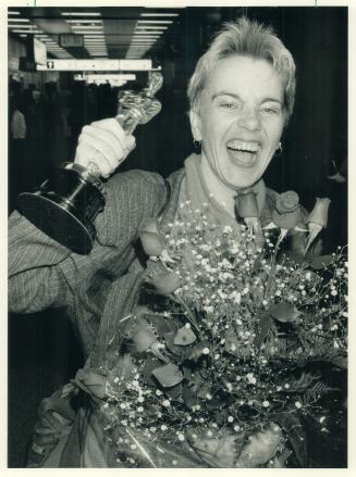 Award-winning smile. Toronto producer-director Brigitte Berman clutches her Oscar for the best documentary feature last night at Pearson Airport as she returned home from Los Angeles