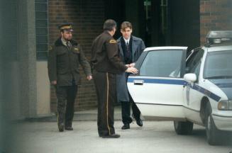 Murder suspect Paul Bernardo is loaded into a police cruiser at the Niagara Region Detention (entre in