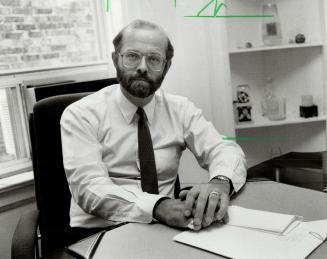 Image shows a politician John Bosley, chairman of International trade subcommittee, sitting at …