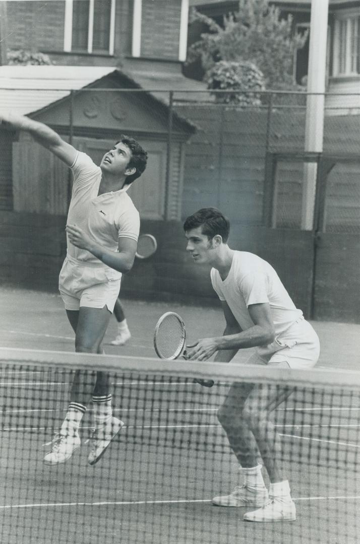 A samashing send-off. Dave Brown (L) of Port Credit leaps to smash ball while partner Chris Burr of London, Ont., keeps tab on play. Regarded as futur(...)