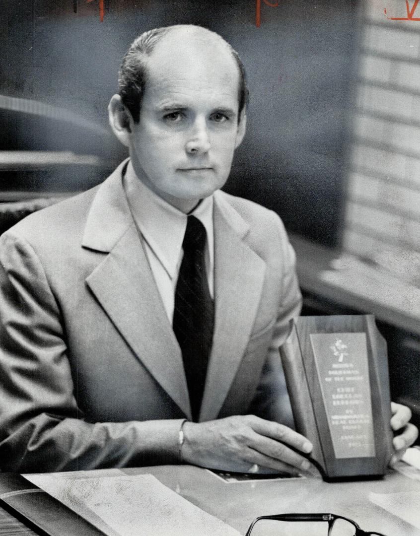 Recently-Appointed chief of the Mississauga Police Force, Douglas Burrows, shows policeman of the month plaque awarded him by Mississauga Real Estate Board