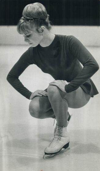 Skater Linda Carbonetto, young protegee of Canada's king of figure skating, Donald Jackson, kneels to check a school figure tracing on ice during trai(...)