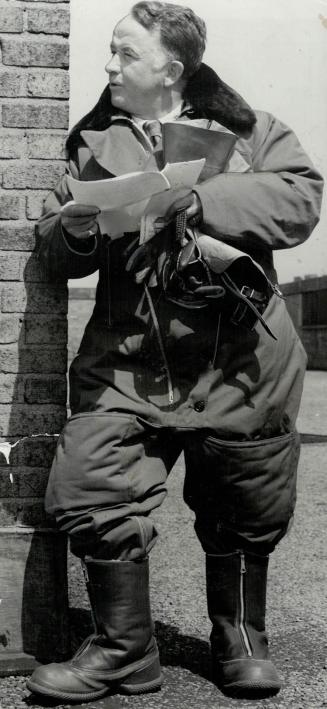 Bundled in his flying suit, Gregory Clark reads a final message before the take off