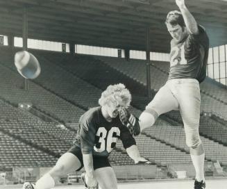 Putting the boot to ball is former Tiger-Cat veteran Tommy Joe Coffey while slotback Ray Langcaster assists him during workout at C.N.E. Stadium. Coff(...)