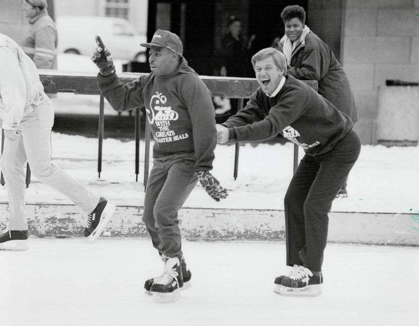 Look who's towing whom: Toronto Argonaut Mike (Pinball) Clemons tows former NHL great Bobby Orr around the ice at Nathan Phillips Square yesterday