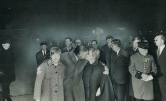 Happily Reunited at London's Heathrow Airport, James Cross kisses his wife, Barbara, as they walk from the plane to the airport lounge. His other arm (...)