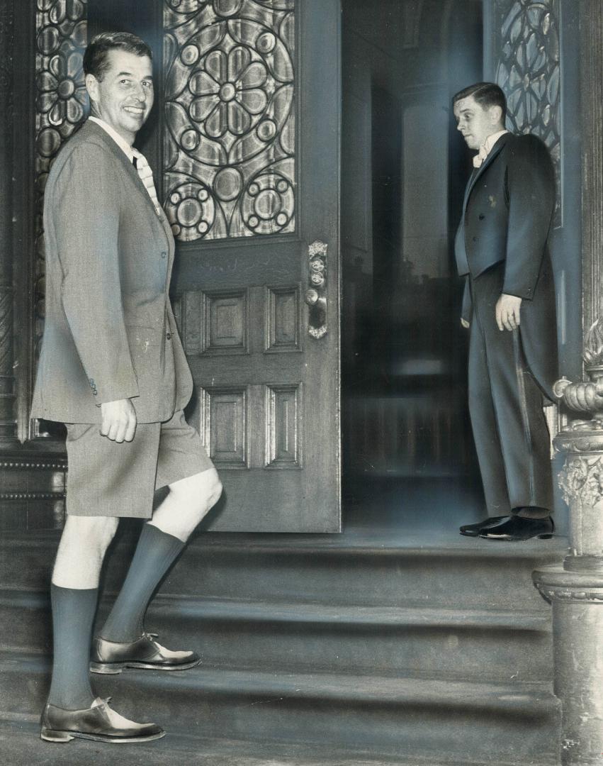 In cool comfort Liberal MPP Donald Deacon enters the Legislature chamber past attendant Peter Edwards today wearing trim Bermuda walking shorts. Clerk(...)