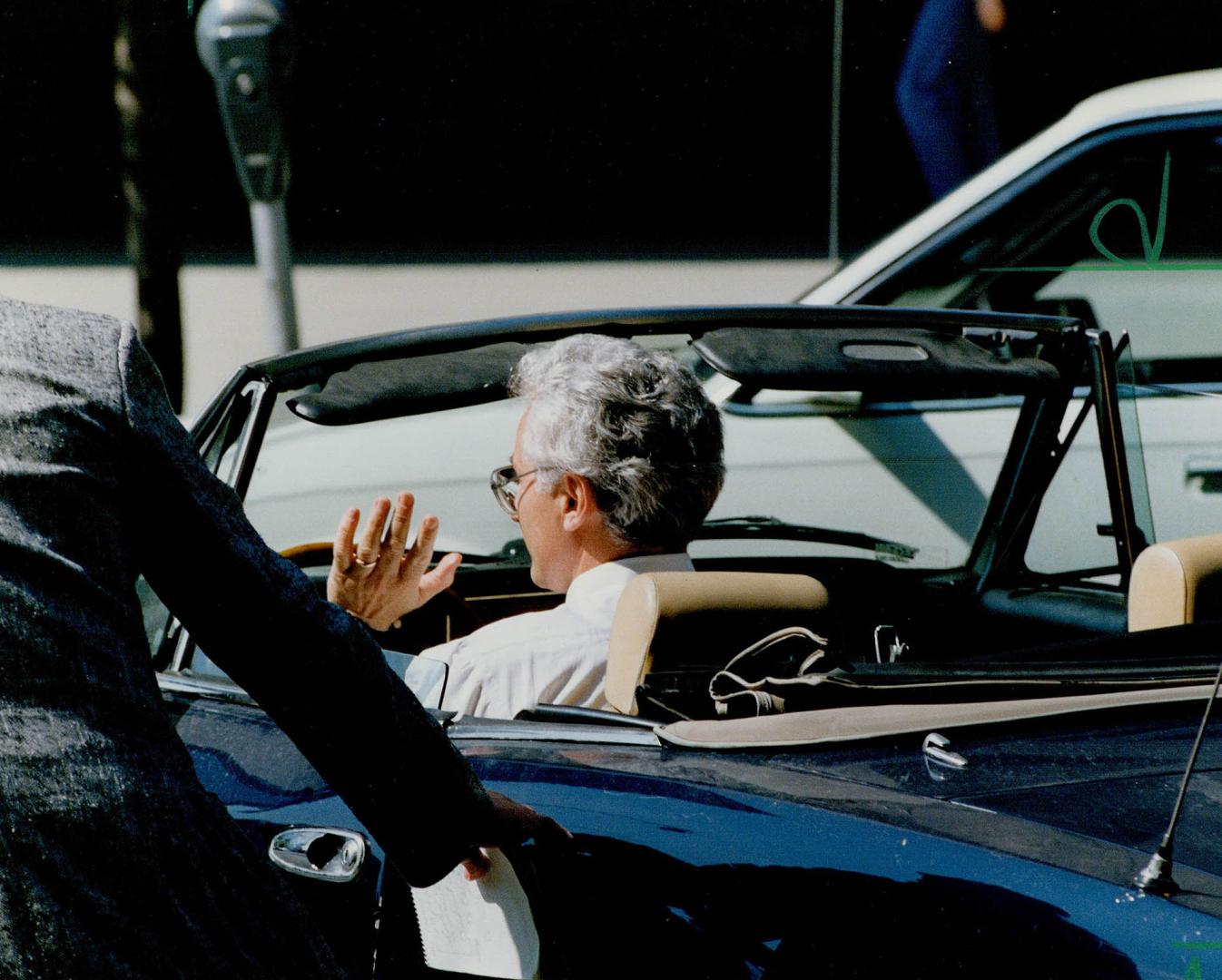 Calls it quits: Provincial Court Judge Lorenzo DiCecco' waves as he drives away in his sports car from the old city hall courthouse yesterday