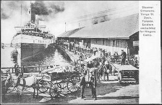 Image shows soldiers embarking on a big ship at the docks.