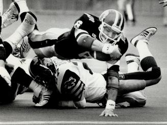 Three TDs for rookie: Argo rookie tailback Gill Fenerty is collared by Ticat conerback Less Browne (above) but eludes this swarm of tacklers (right) to score one of his three TDs on the afternoon