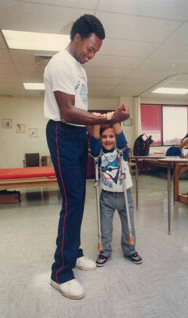 Tony Fernandez, recovering from an elbow injury, gets a helping hand from his buddy Javier Roldan, above