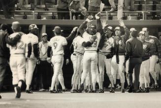 High-fives all around: Jays' designated hitter Cecil Fielder (23) accepts some well-deserved praise from his teammates after crushing a game-winning tater yesterday in the 10th inning