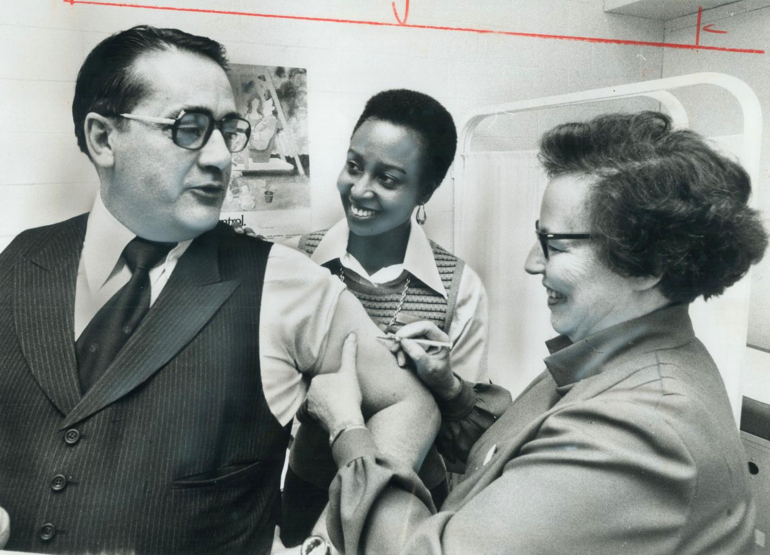 Mayor gets his shot. Mayor Dennis Flynn is inoculated against swine flu by public health nurse Marie Nelson while nurse Sylvia Williams watches. Only (...)