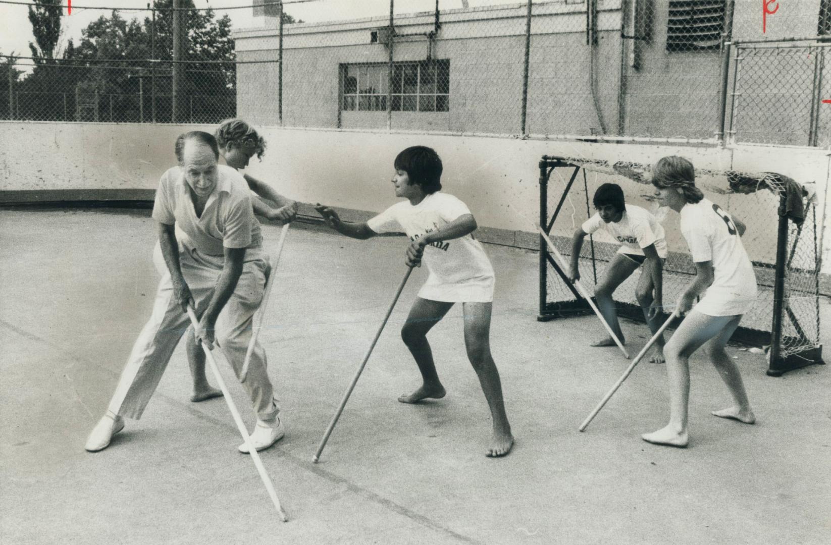 Training for the Special Olympics for the mentally retarded, young athletes play floor hockey yesterday with Harry (Red) Foster, a millionaire adverti(...)