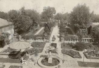 Aerial view of courtyard showing symmetrical garden layout, including stone pathways, fences, u…