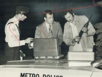 Sgt. John Luby checks high-powered rifle seized at scene