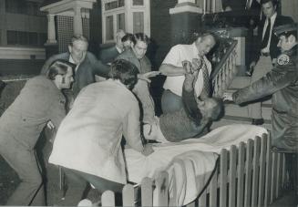 Detective Bert Novis grasps the wrist of a wounded man flushed out of a Howland Ave