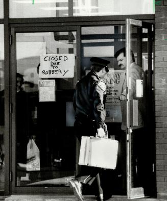 Bank closed: Toronto Dominion bank branch sports a Closed Due To Robbery sign in its window as one policeman lets a fellow officer in to conduct an investigation