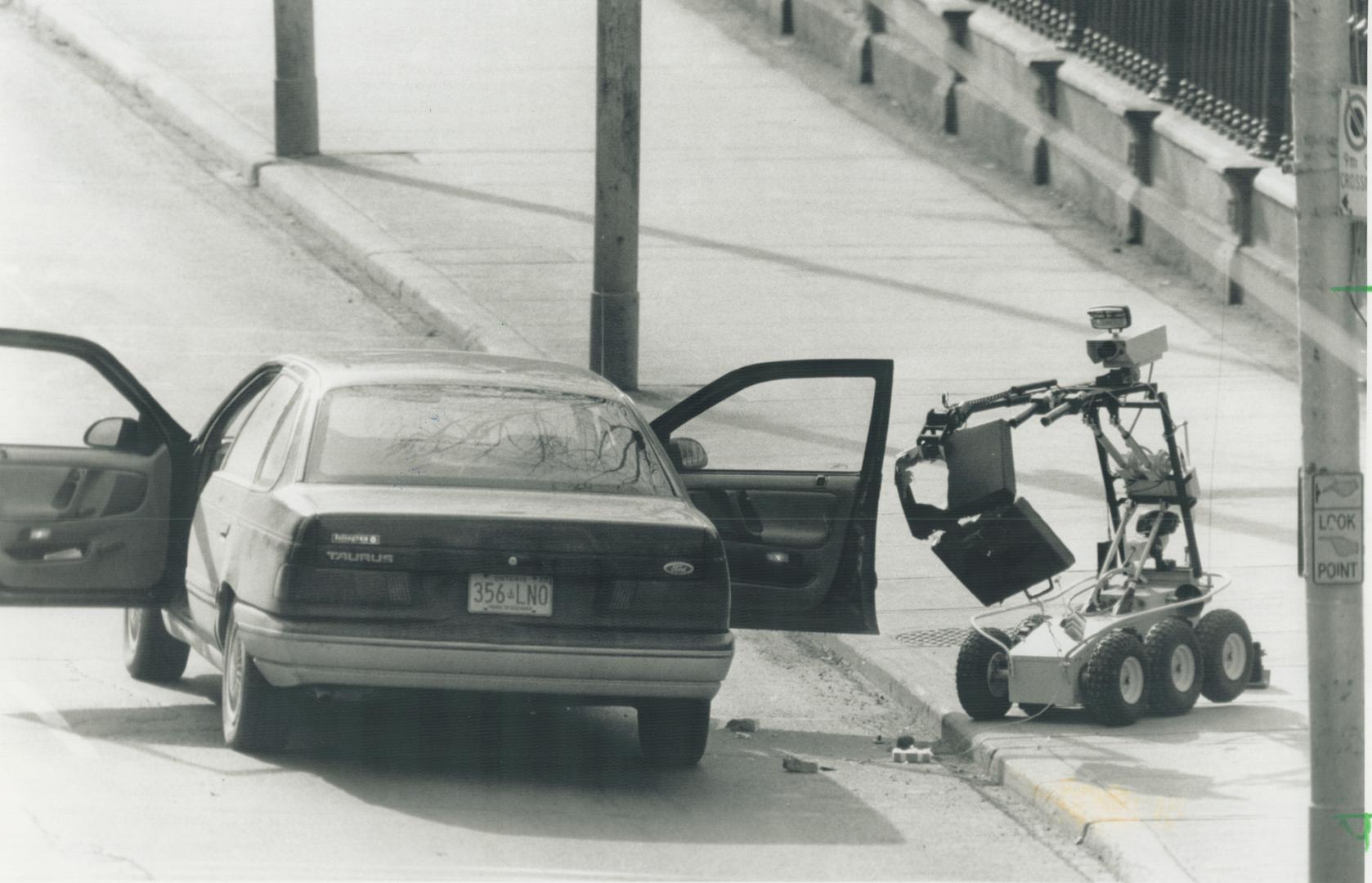 Robot's Help: A remote-control device directed by police officers shakes open a briefcase, after blasting it apart with a shotgun