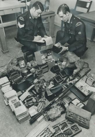 Loot from Robberies in Markham, returned to police headquarters by four juveniles who were caught after a three-month crime spree, is checked by Sgt. (...)