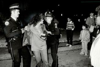 Abduction scare: A woman comforts two children, left, while police arrest another woman after stopping a buson its way to a prayer meeting at the Eglinton Gospel Hall last night